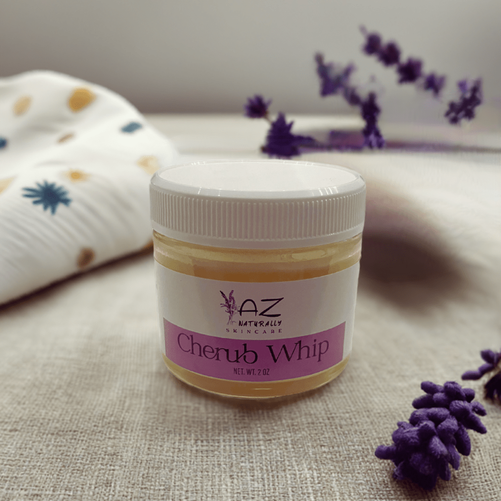 Jar of 'Cherub Whip' diaper rash treatment with purple flowers and a blanket on a light grey surface