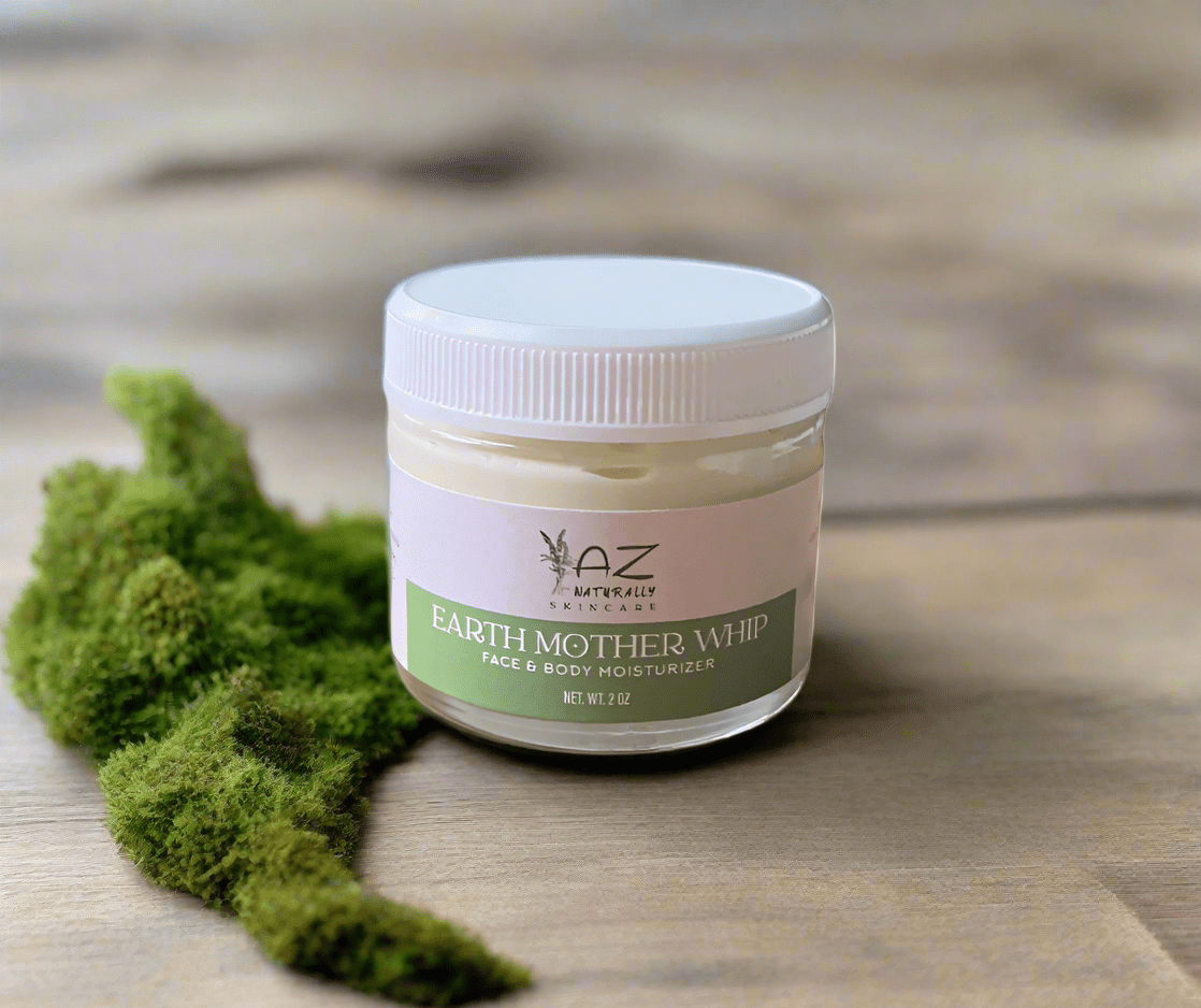 Jar of 'EARTH MOTHER WHIP' face and body moisturizer adjacent to moss on a wooden surface