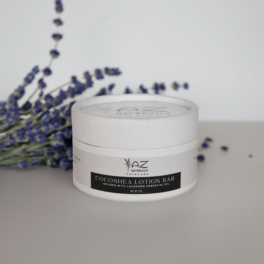 Jar of 'Handcrafted Cocoshea Lotion Bar' on a light gray surface with purple flowers in the background 